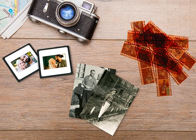 Starý fotoaparát, diapozitívy s farebnými fotografiami, čiernobiele fotografie a hromada negatívov na drevenom stole