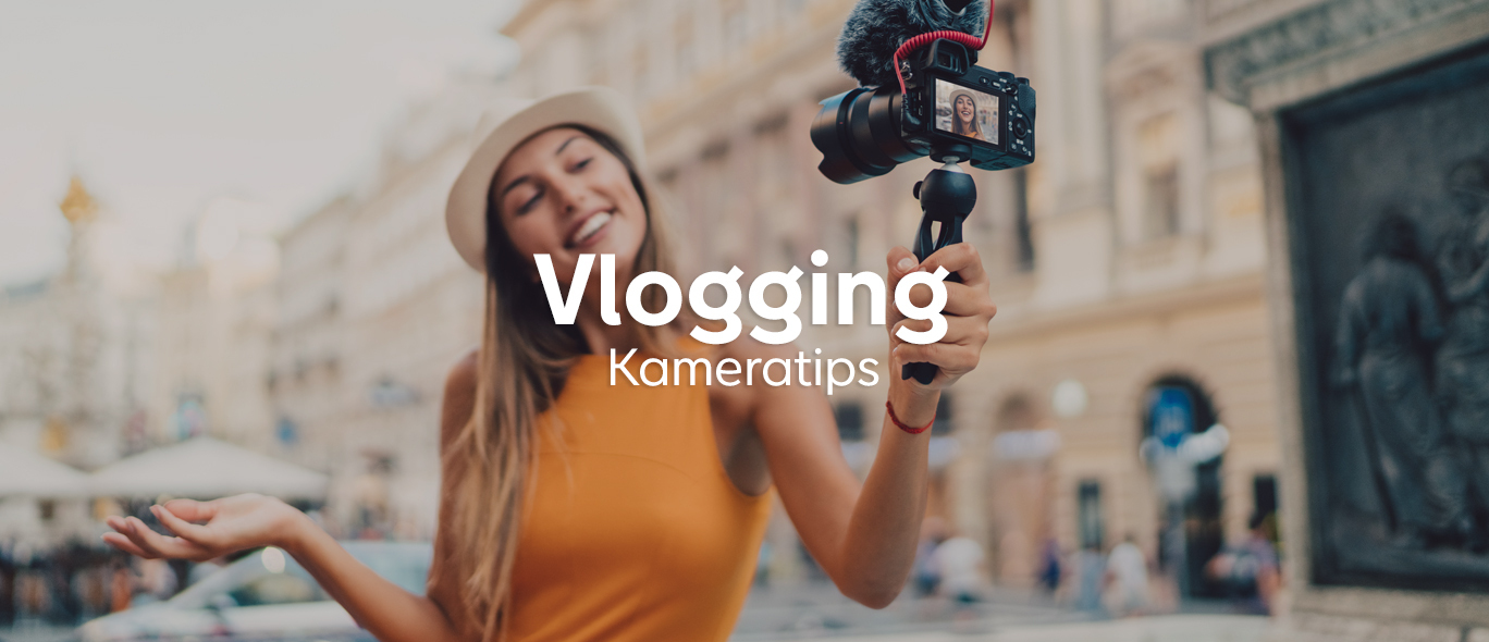 Žena v klobúku a oranžových šatách drží kameru na stabilizátore a natáča video na ulici v meste.