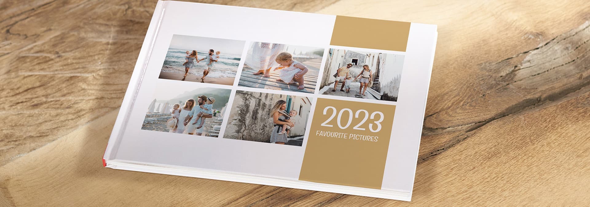 Fotokniha na drevenom stole so stránkami znázorňujúcimi štyri fotografie rodinných chvíľ pri mori a nápisom „2023 Favourite Pictures“ v zlatej farbe
