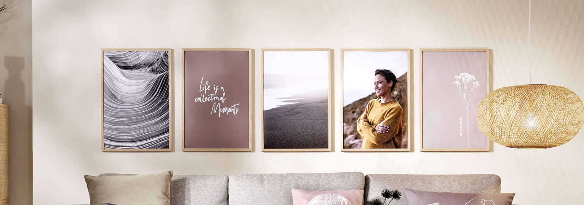 Galéria piatich rámov s fotografiami a citátmi zavesená na stene nad pohovkou v obývacej izbe