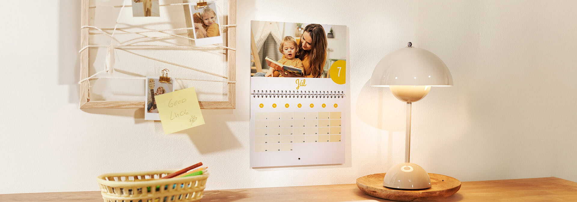 Nástenný kalendár s rodinnou fotografiou, vedľa neho dekorácia s fotkami a poznámkovými lístkami