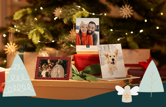 Vianočné pohľadnice a kalendár so zimnými motívmi na darčekovej škatuli, pri ozdobenom vianočnom stromčeku