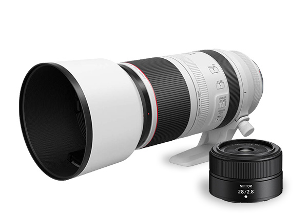 Dlhý biely teleobjektív s červeným prúžkom vedľa menšieho čierneho objektívu s ohniskovou vzdialenosťou 28 mm f/2.8